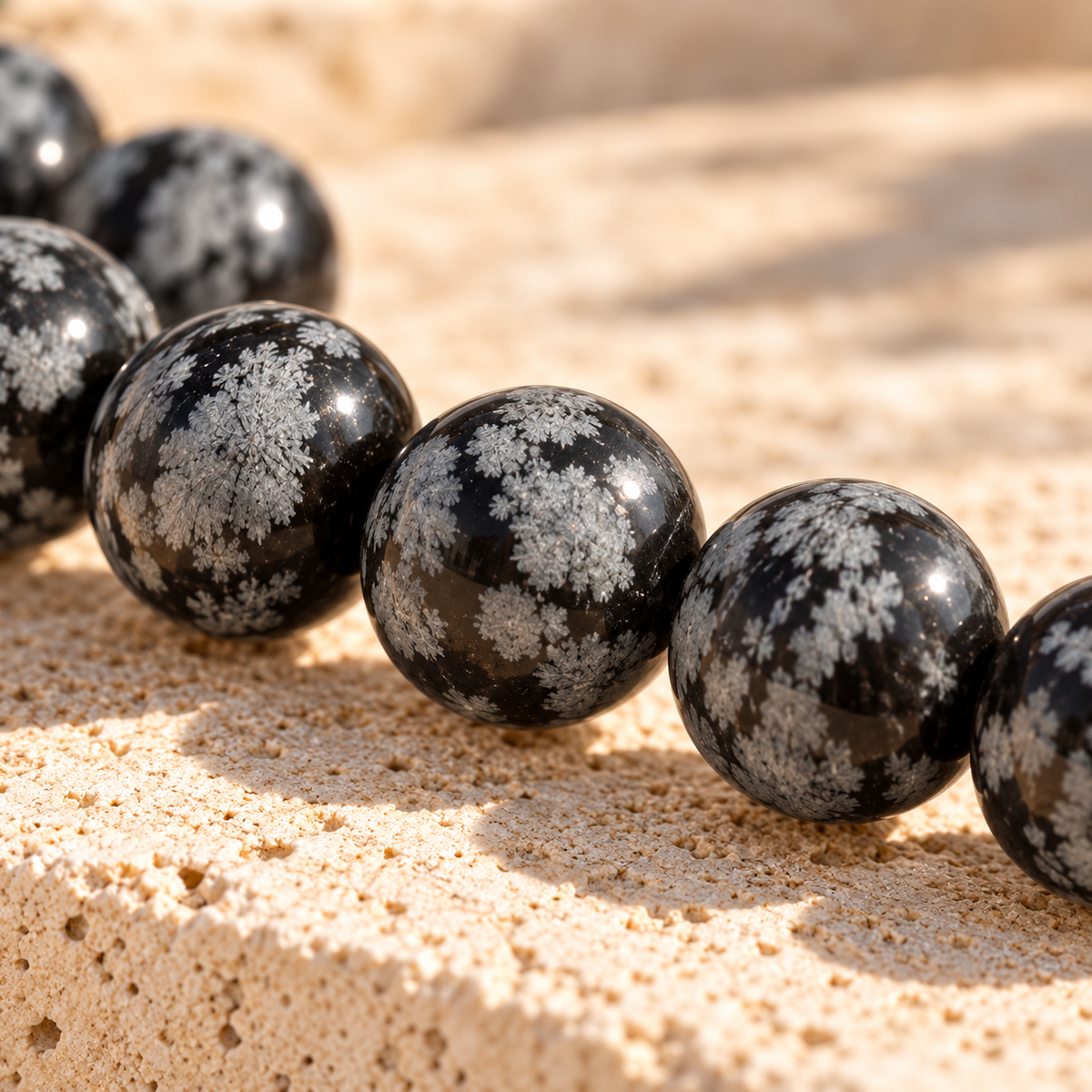 Gros plan sur les perles en obsidienne flocon de neige naturelle, motifs gris et noirs, Atelier Sémio.